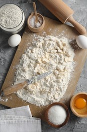 Photo of Making shortcrust pastry. Different ingredients for dough, knife and rolling pin on grey table, top view