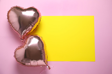 Heart shaped balloons and yellow card on pink background, flat lay. Space for text