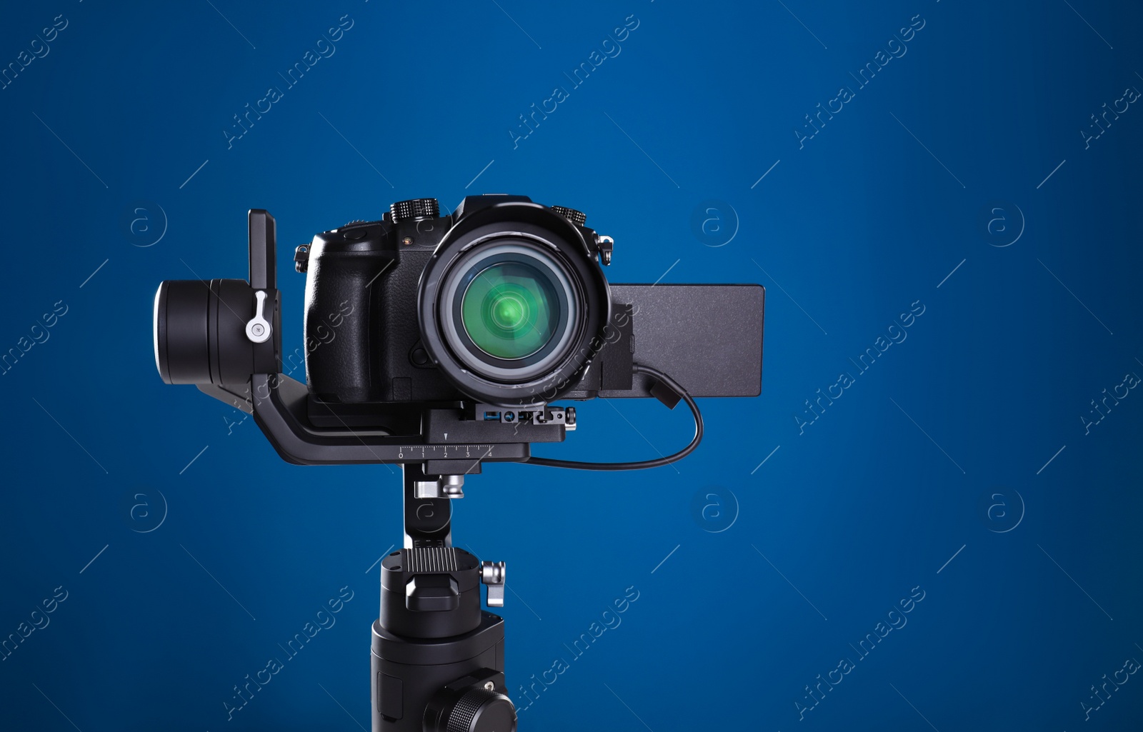 Photo of Modern professional video camera on blue background