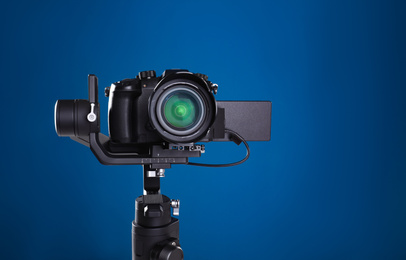 Modern professional video camera on blue background