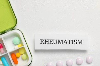 Photo of Card with word Rheumatism and pills on white background, flat lay. Space for text