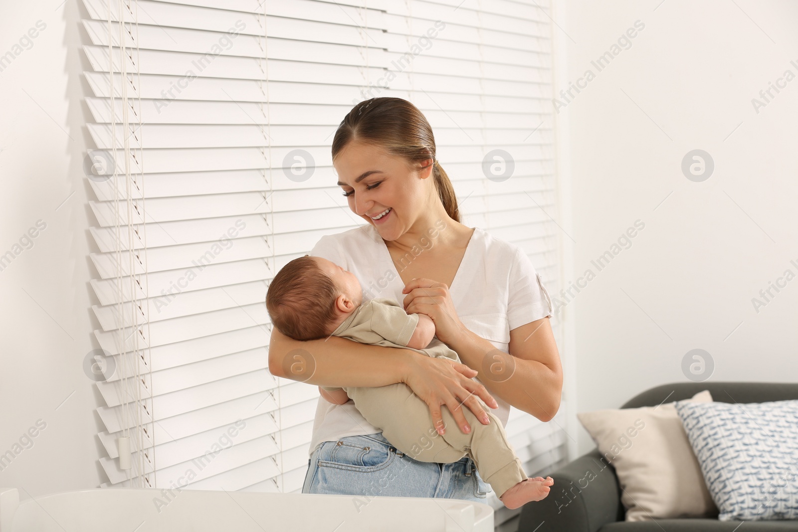 Photo of Mother feeding her cute child with infant formula indoors