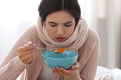 Photo of Sick young woman eating soup to cure flu at home