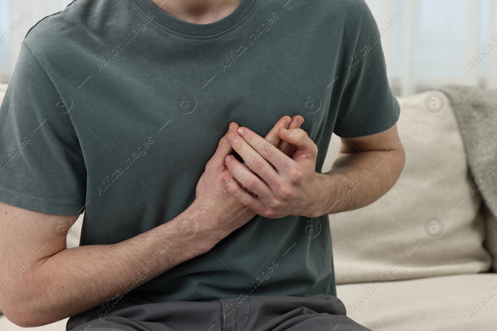 Photo of Man suffering from heart hurt on sofa at home, closeup