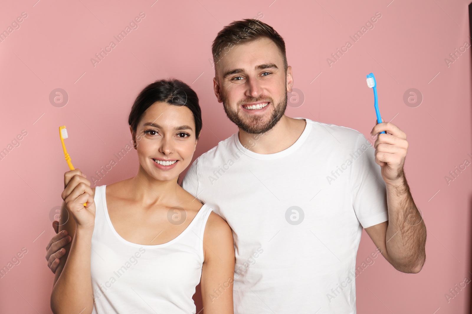 Photo of Young couple with toothbrushes on color background. Teeth care