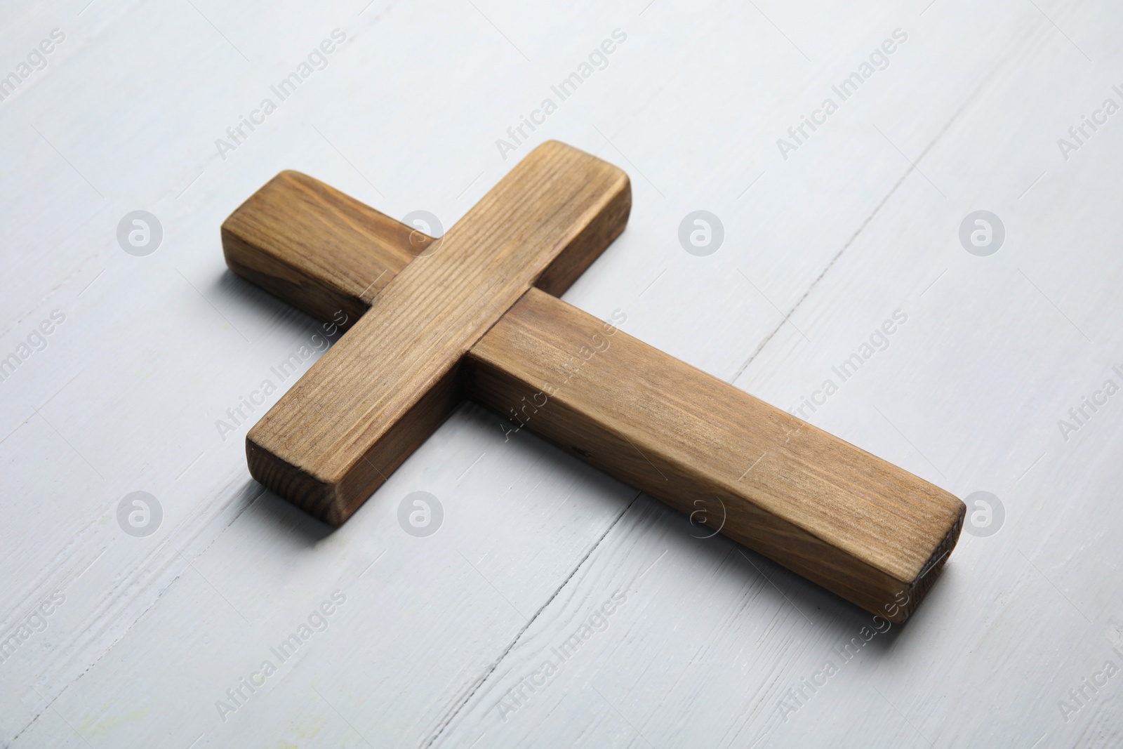 Photo of Christian cross on white wooden background, closeup. Religion concept
