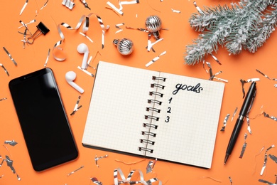Word Goals in notebook, new aims. Objects on orange background, flat lay