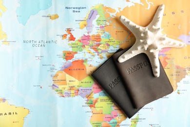 Photo of Passports and sea star on world map, top view. Travel agency