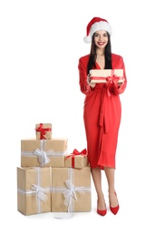 Woman in red dress and Santa hat with Christmas gifts on white background