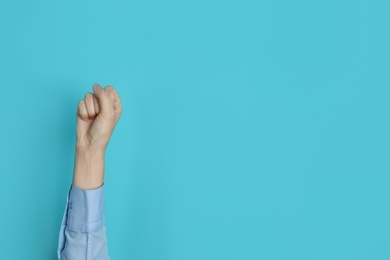 Photo of Young woman showing clenched fist on color background. Space for text