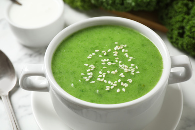 Photo of Tasty kale soup with sesame seeds on white marble table, closeup