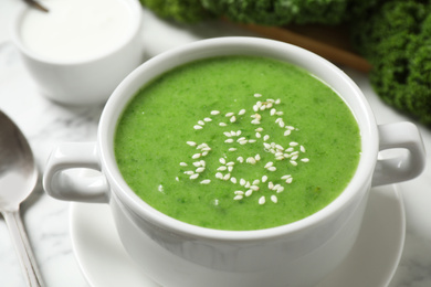 Tasty kale soup with sesame seeds on white marble table, closeup