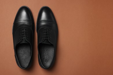 Photo of Pair of leather men shoes on brown background, top view. Space for text