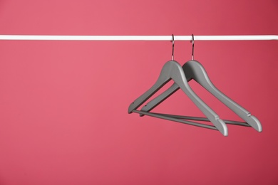 Photo of Empty clothes hangers on metal rail against color background. Space for text