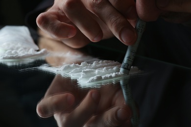 Drug addict taking cocaine at table, closeup view