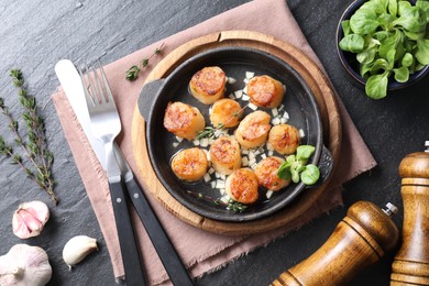 Delicious fried scallops in dish served on dark gray textured table, flat lay