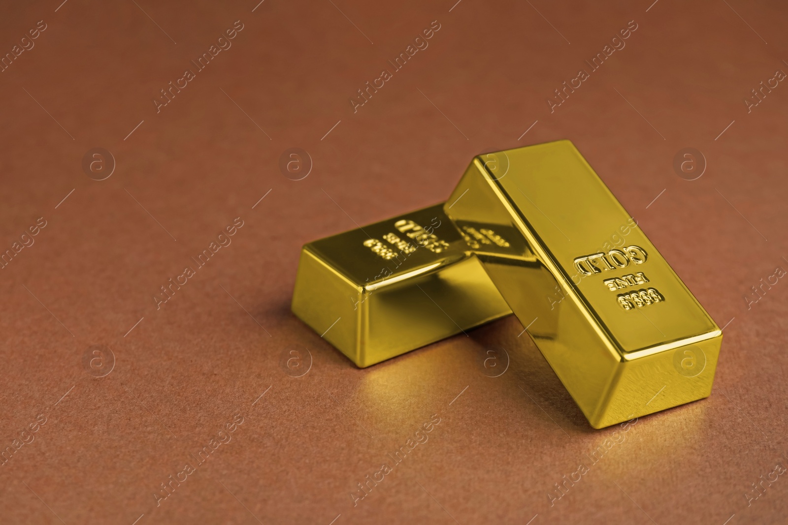 Photo of Shiny gold bars on brown background. Space for text