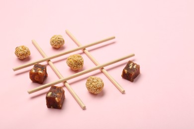 Photo of Tic tac toe game made with sweets on pink background