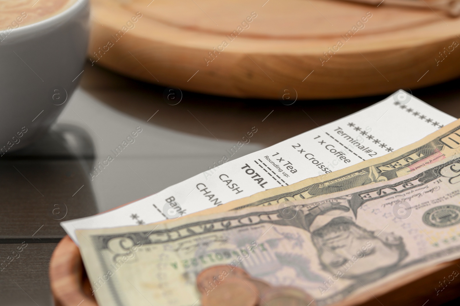 Photo of Tips and receipt on wooden table, closeup