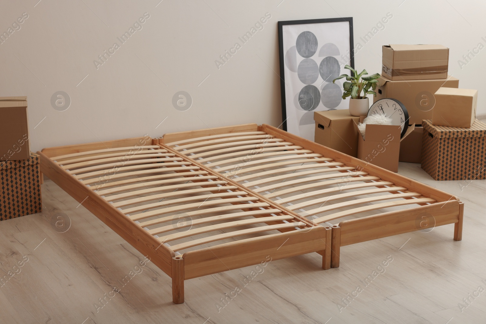 Photo of Wooden bed frame and cardboard boxes on floor in room