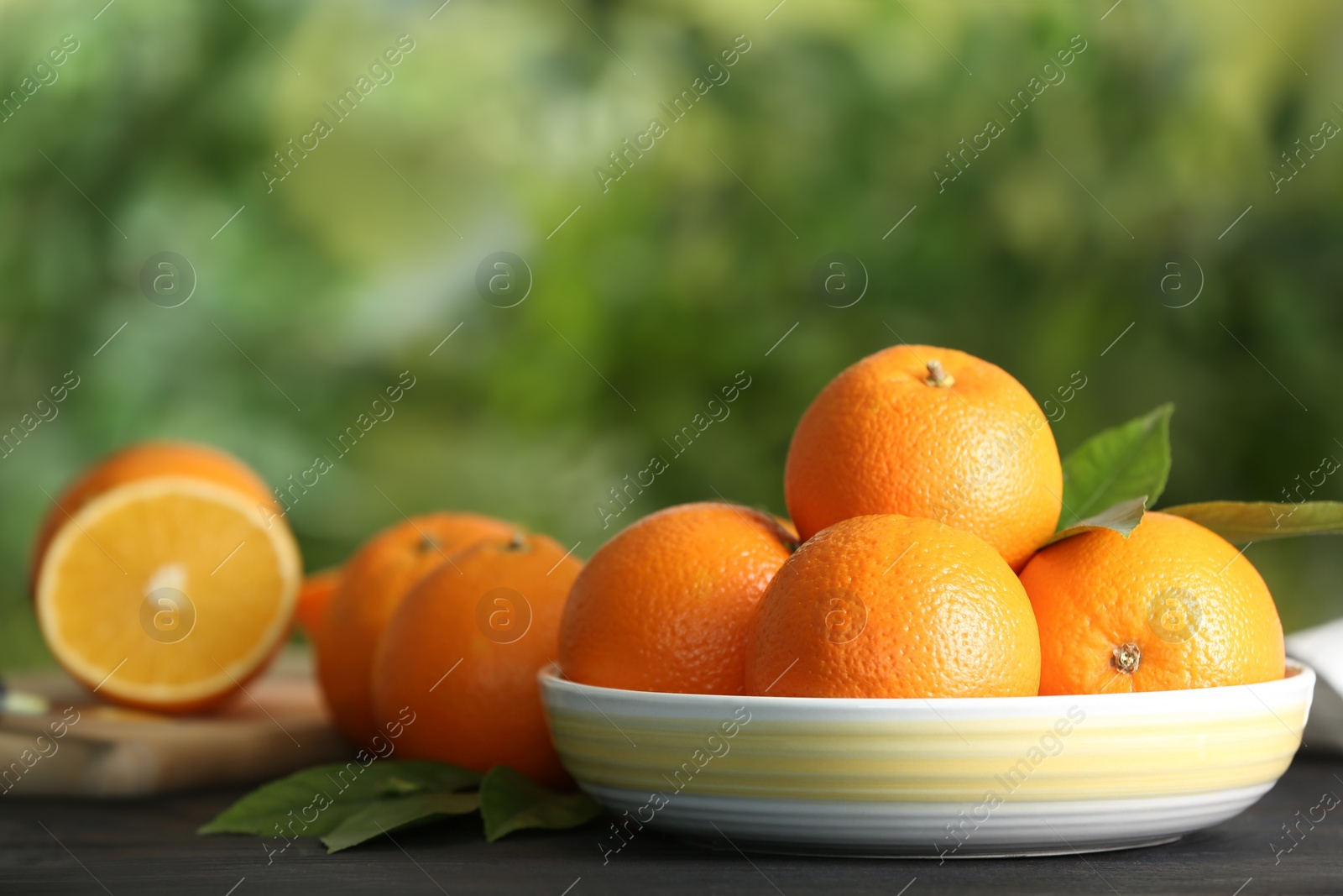 Photo of Fresh ripe oranges on wooden table against blurred background. Space for text