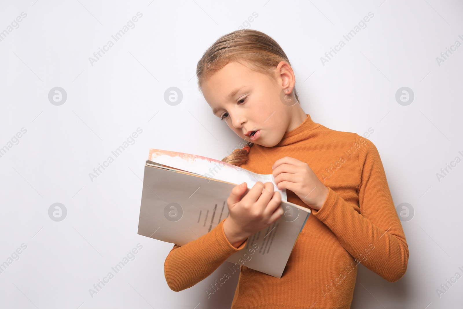 Photo of Emotional little girl reading book on white background. Space for text