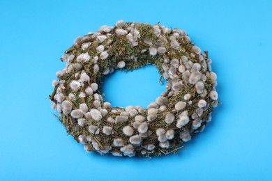 Wreath made of beautiful willow flowers on light blue background