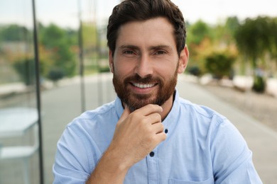Photo of Portrait of happy handsome bearded man outdoors
