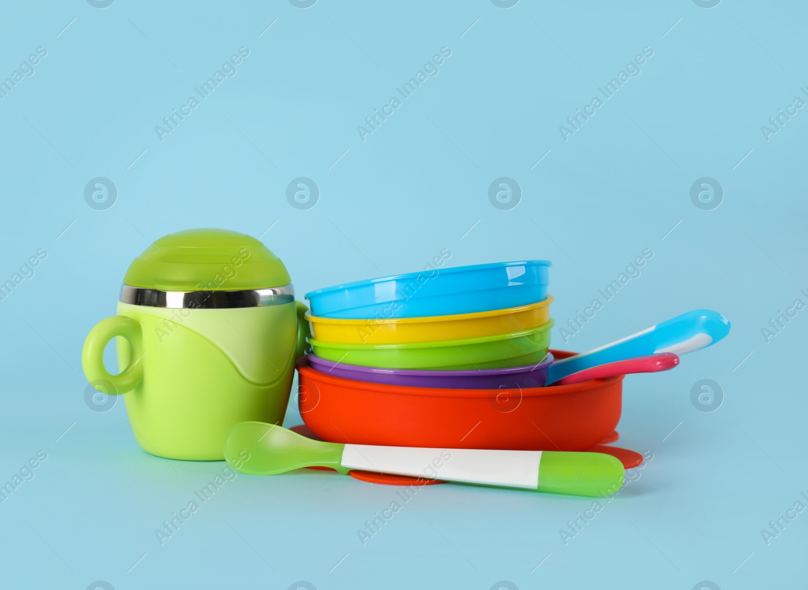 Photo of Set of plastic dishware on light blue background. Serving baby food