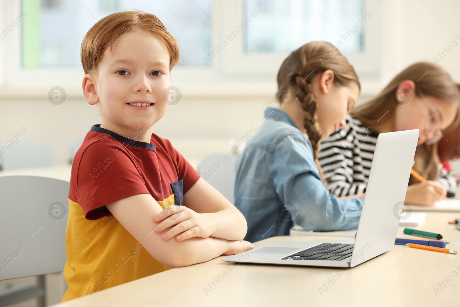 Photo of Smiling boy with his classmates studying in classroom at school