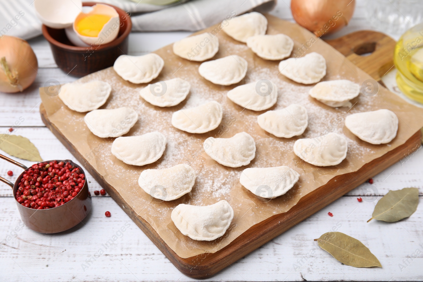 Photo of Raw dumplings (varenyky) with tasty filling and ingredients on white wooden table