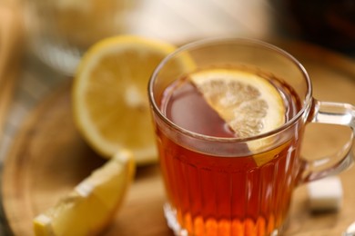 Photo of Glass mug of aromatic tea with lemon on board, closeup. Space for text