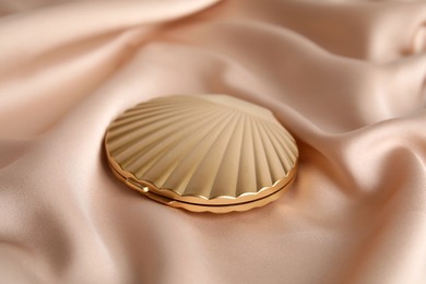 Photo of Bright cosmetic pocket mirror on rose gold fabric