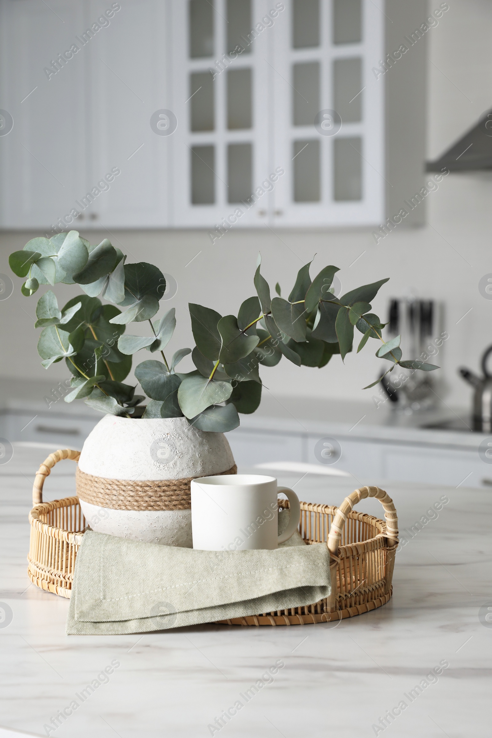 Photo of Vase with beautiful eucalyptus branches on white marble table in kitchen