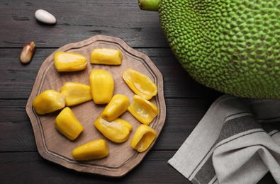 Photo of Fresh exotic jackfruit on black wooden table, flat lay