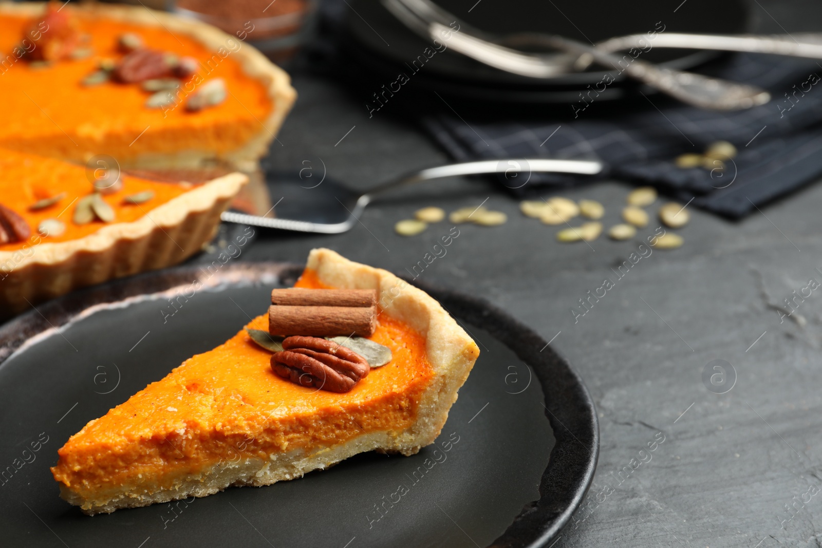 Photo of Slice of delicious homemade pumpkin pie on black table