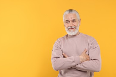 Photo of Portrait of handsome senior man on orange background. Space for text