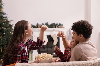 Family with popcorn spending time together at home. Watching movie via video projector