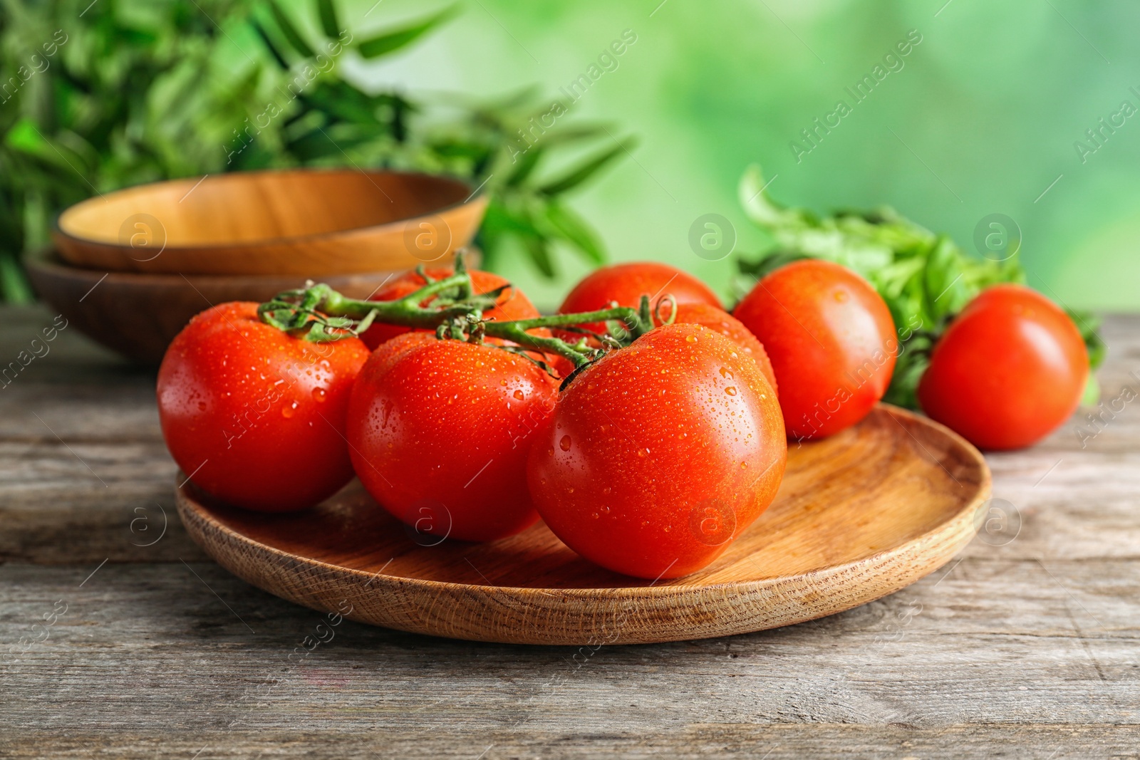 Photo of Plate with fresh ripe tomatoes on wooden table