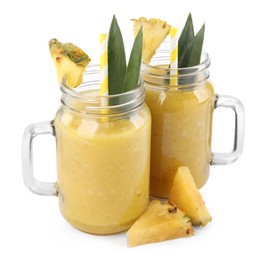 Photo of Tasty pineapple smoothie in mason jars and sliced fruit isolated on white