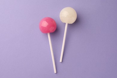 Photo of Tasty lollipops on violet background, flat lay