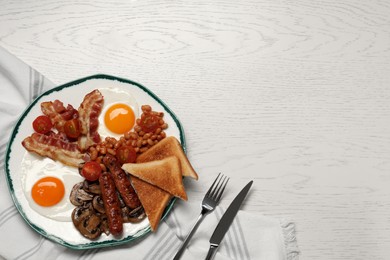 Photo of Plate of fried eggs, mushrooms, beans, bacon, sausages and toasts served on white wooden table, flat lay with space for text. Traditional English breakfast