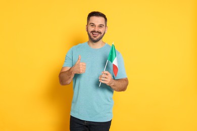 Photo of Man with flag of Italy showing thumb up on yellow background