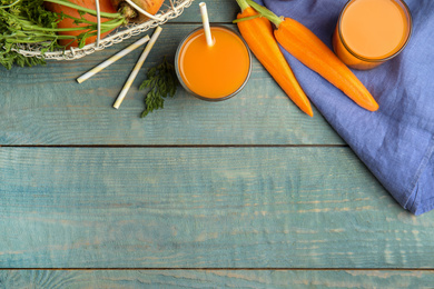 Photo of Freshly made carrot juice on wooden table, flat lay. Space for text