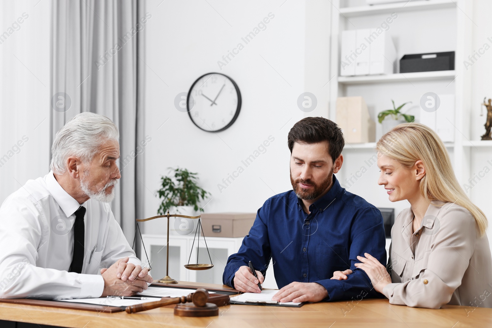 Photo of Couple signing document at table in lawyer's office