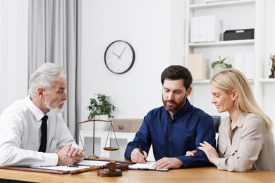 Couple signing document at table in lawyer's office