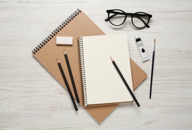 Photo of Flat lay composition with blank sketchbook on white wooden table