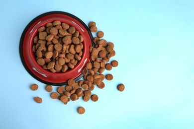 Dry dog food and feeding bowl on light blue background, flat lay. Space for text