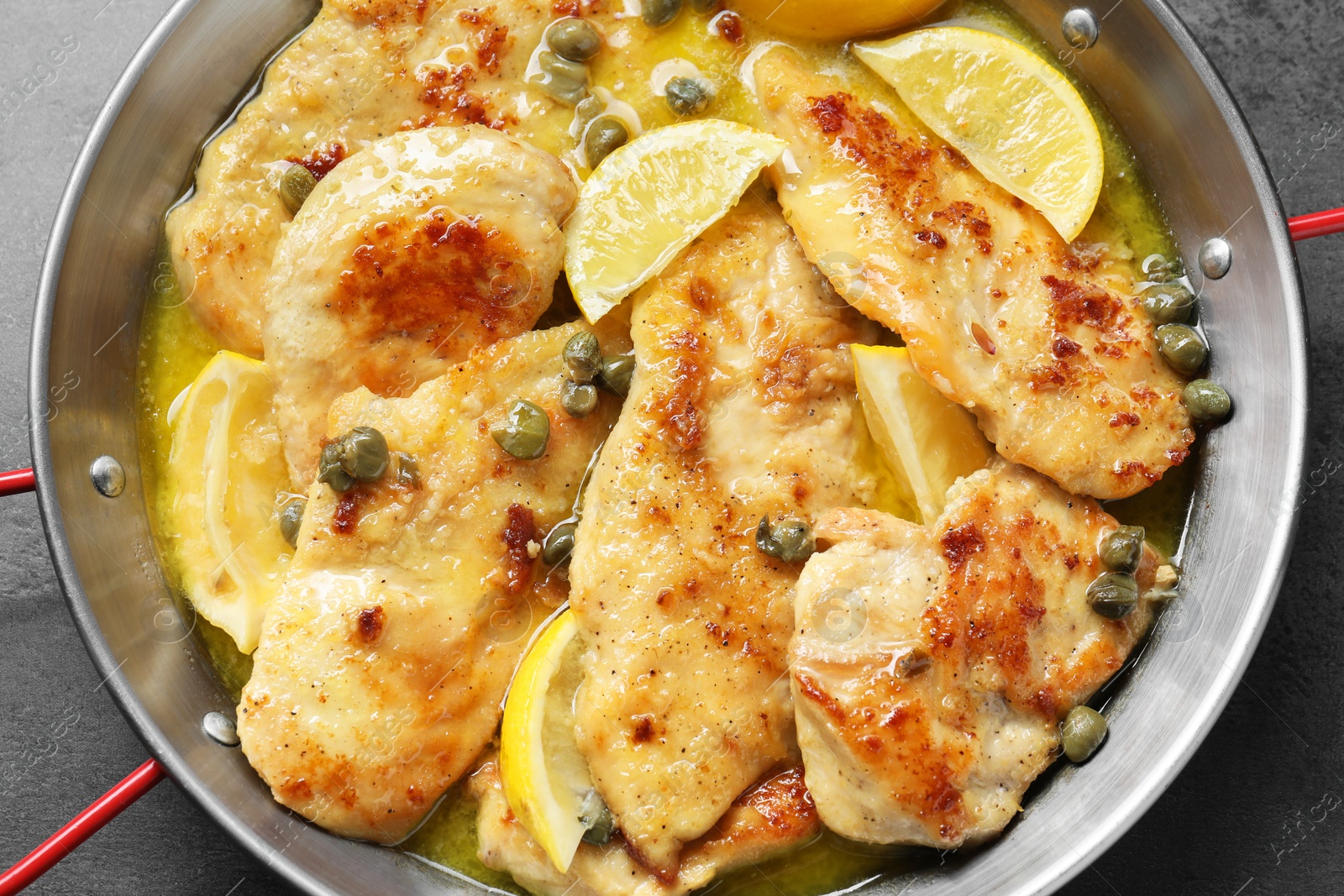 Photo of Delicious chicken piccata with lemons on grey table, top view