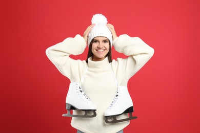 Photo of Happy woman with ice skates on red background